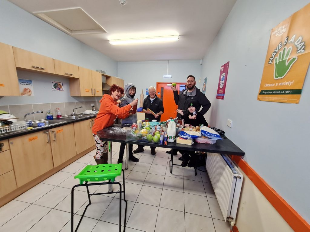 Members of the GROW team standing behind a table full of food in the kitchen